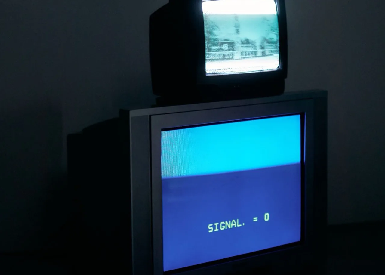 Two CRT screens stacked in a dark room; the lower one displays the text SIGNAL = 0 in green over blue.