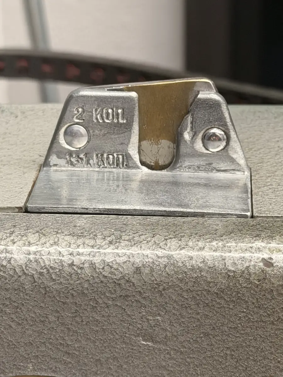 Close-up of the coin slot on the face of the phone. The cast plate is stamped 15 КОП and 2 КОП, and the slot itself has been filed wider, leaving bright bare metal against the weathered surface.