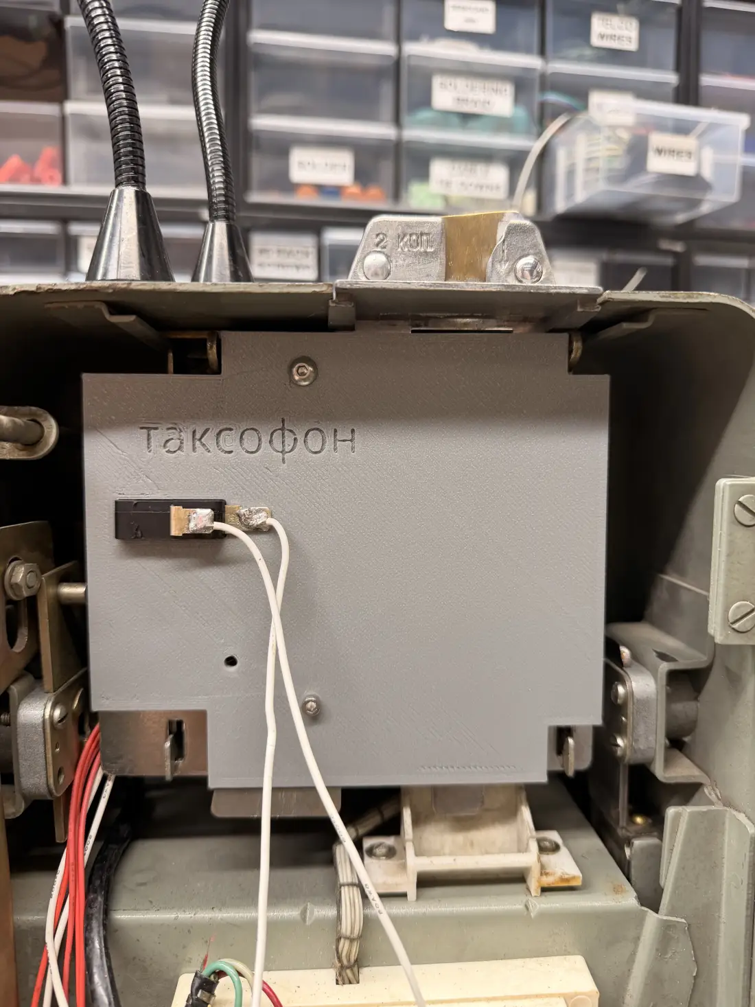 The finished 3D-printed coin mechanism installed inside the phone, a flat grey panel with the word Таксофон embossed on its face and a microswitch wired to it. The original 2-kopeck coin bracket is visible above.